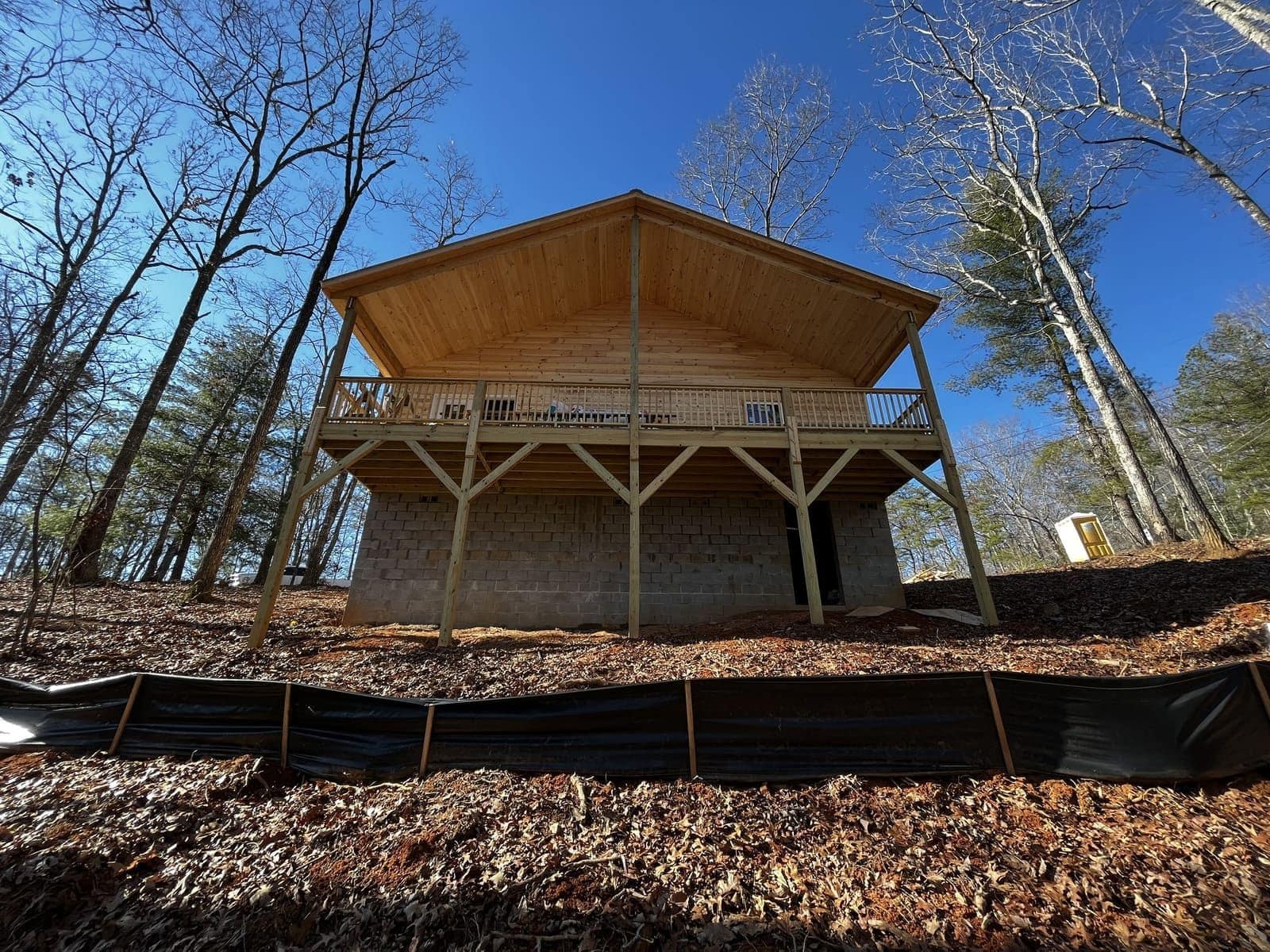 Wood cabin on a block foundation with a deck above a wooded slope