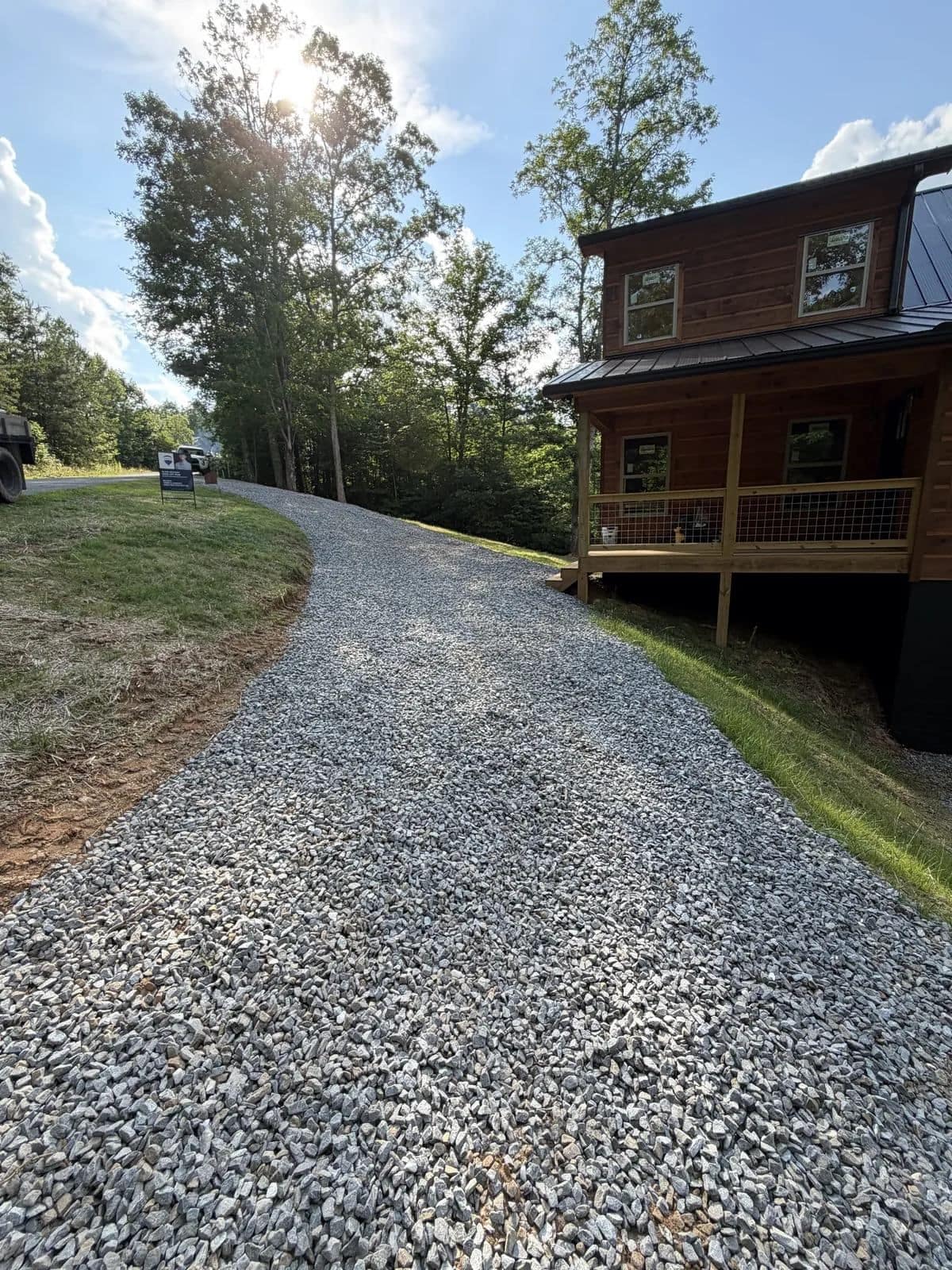 Brown wood-sided home with a covered porch at the top of a gravel driveway