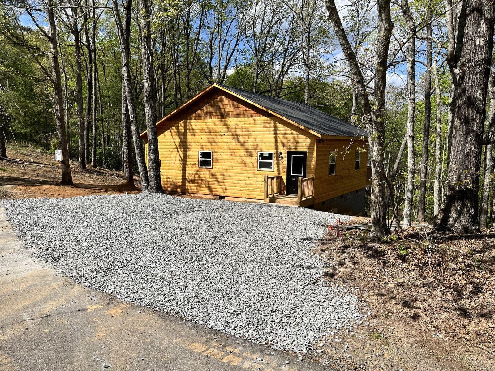 Wood-sided cabin with gravel driveway in a wooded lot