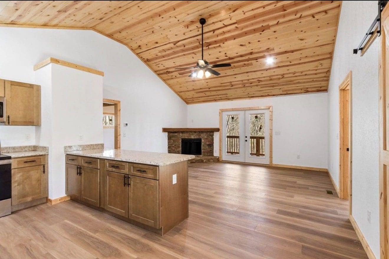 Open living area with wood ceiling, kitchen island and fireplace