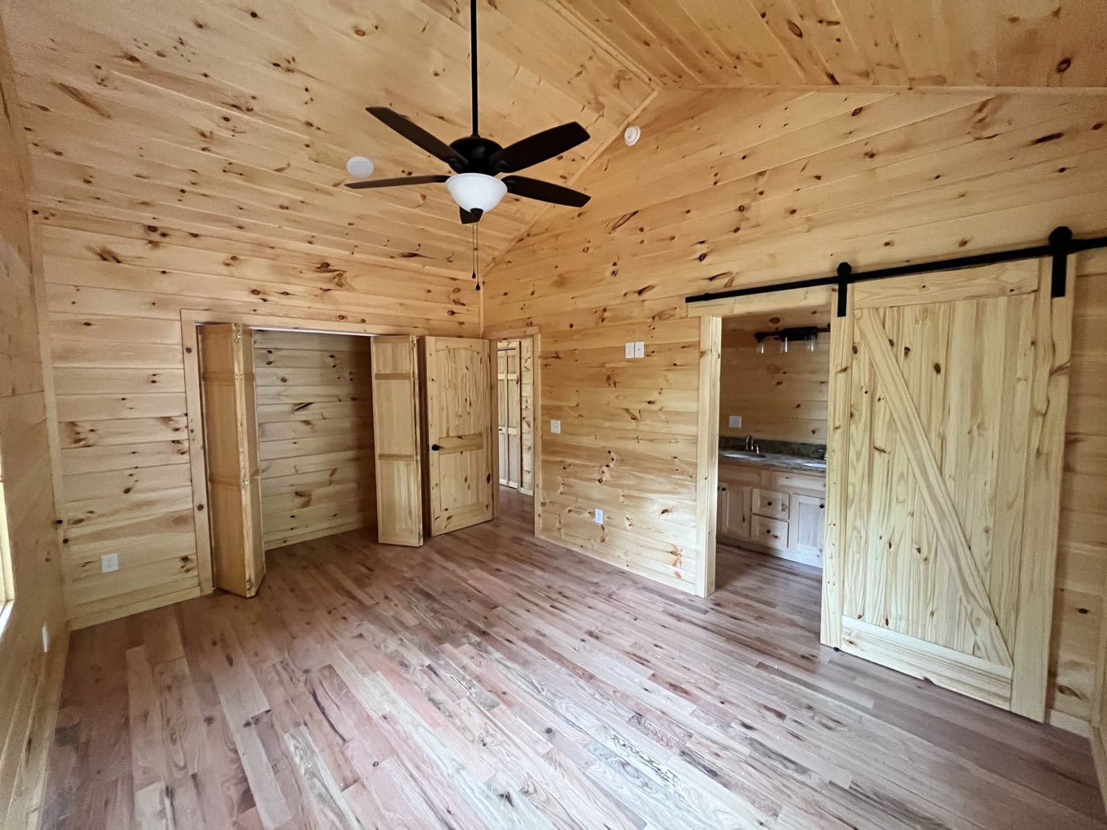 Pine-paneled room with ceiling fan and sliding barn doors
