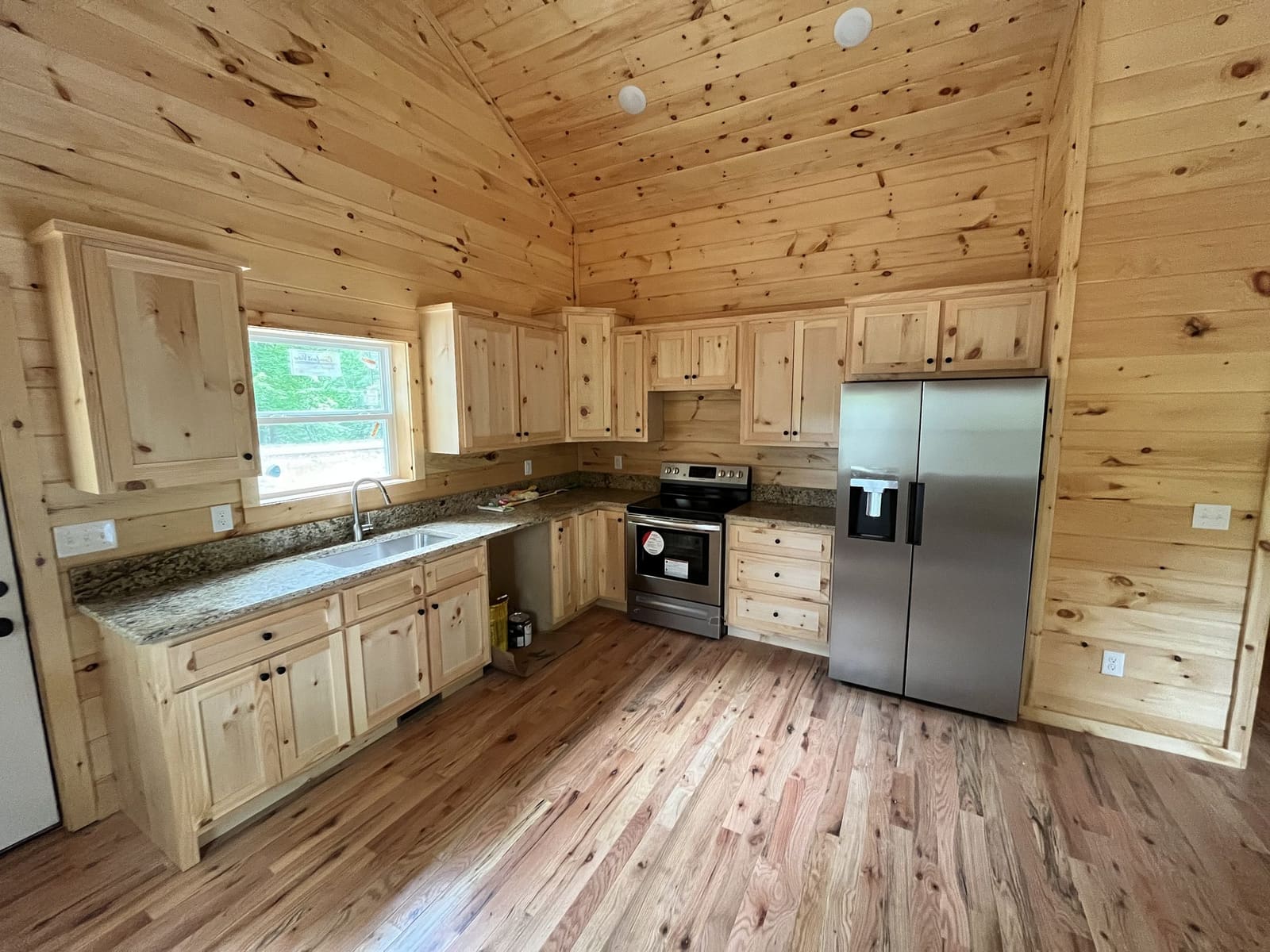 Cabin kitchen with pine cabinets, granite counters and stainless appliances