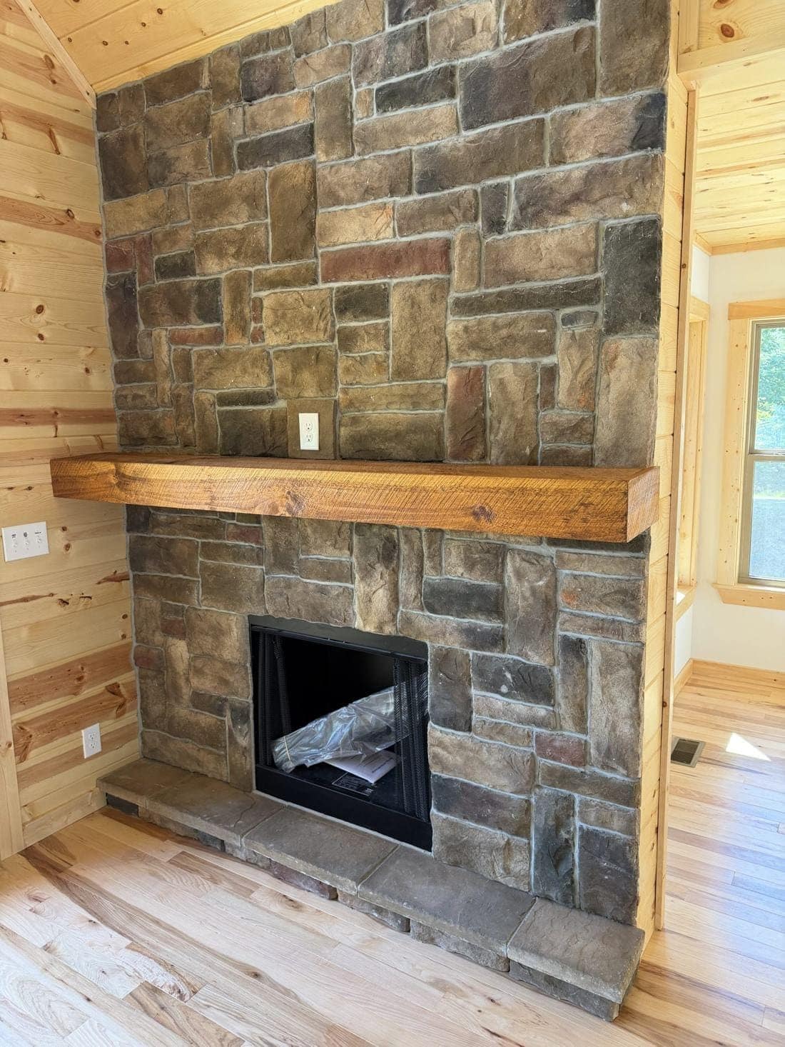 Stone fireplace with wood mantel and pine walls