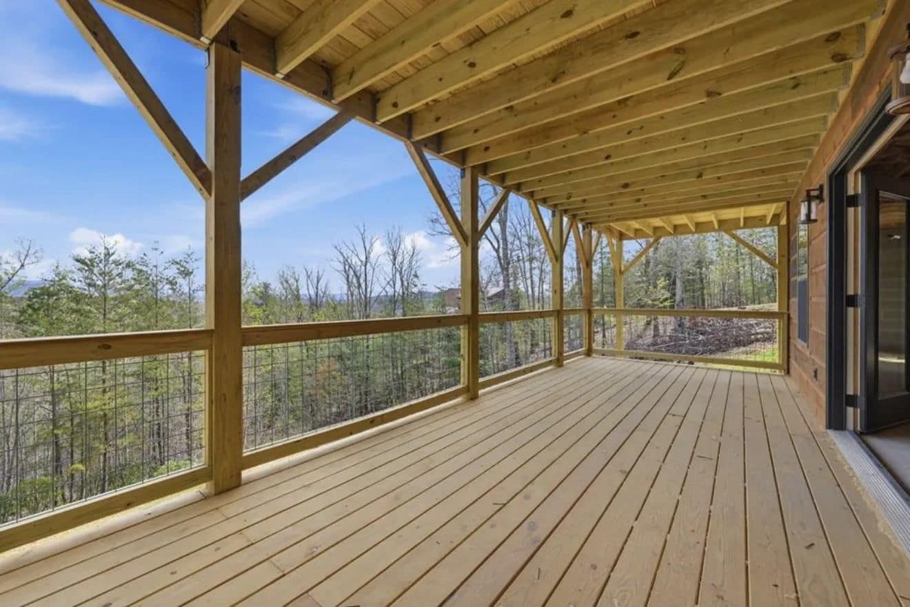 Covered wood deck with timber posts and railing looking out over trees and distant hills